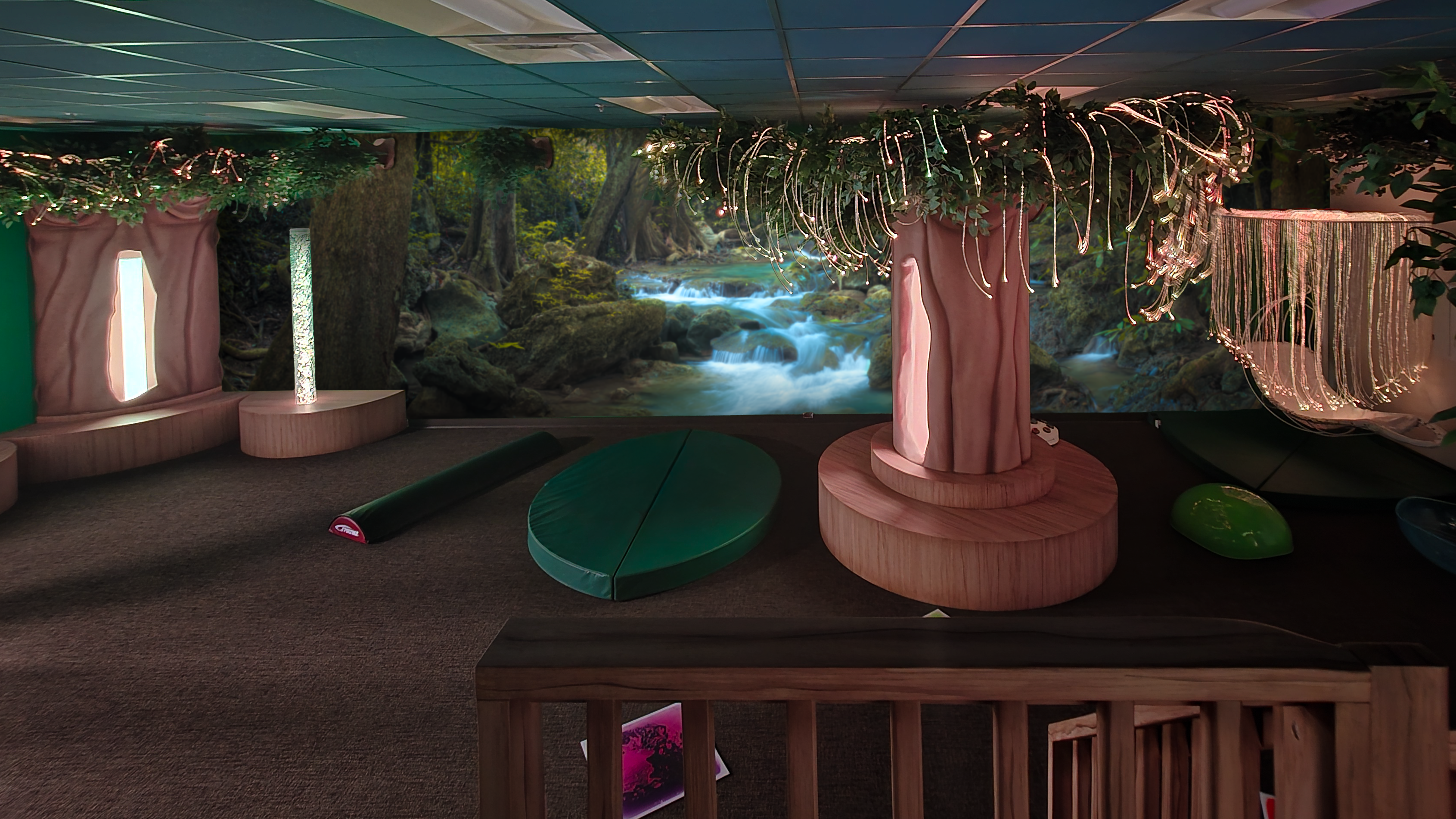 Immersive sensory room with woodland-themed murals, interactive lighting, bubble tubes, fiber optics, and custom sensory features designed for children with diverse sensory needs.