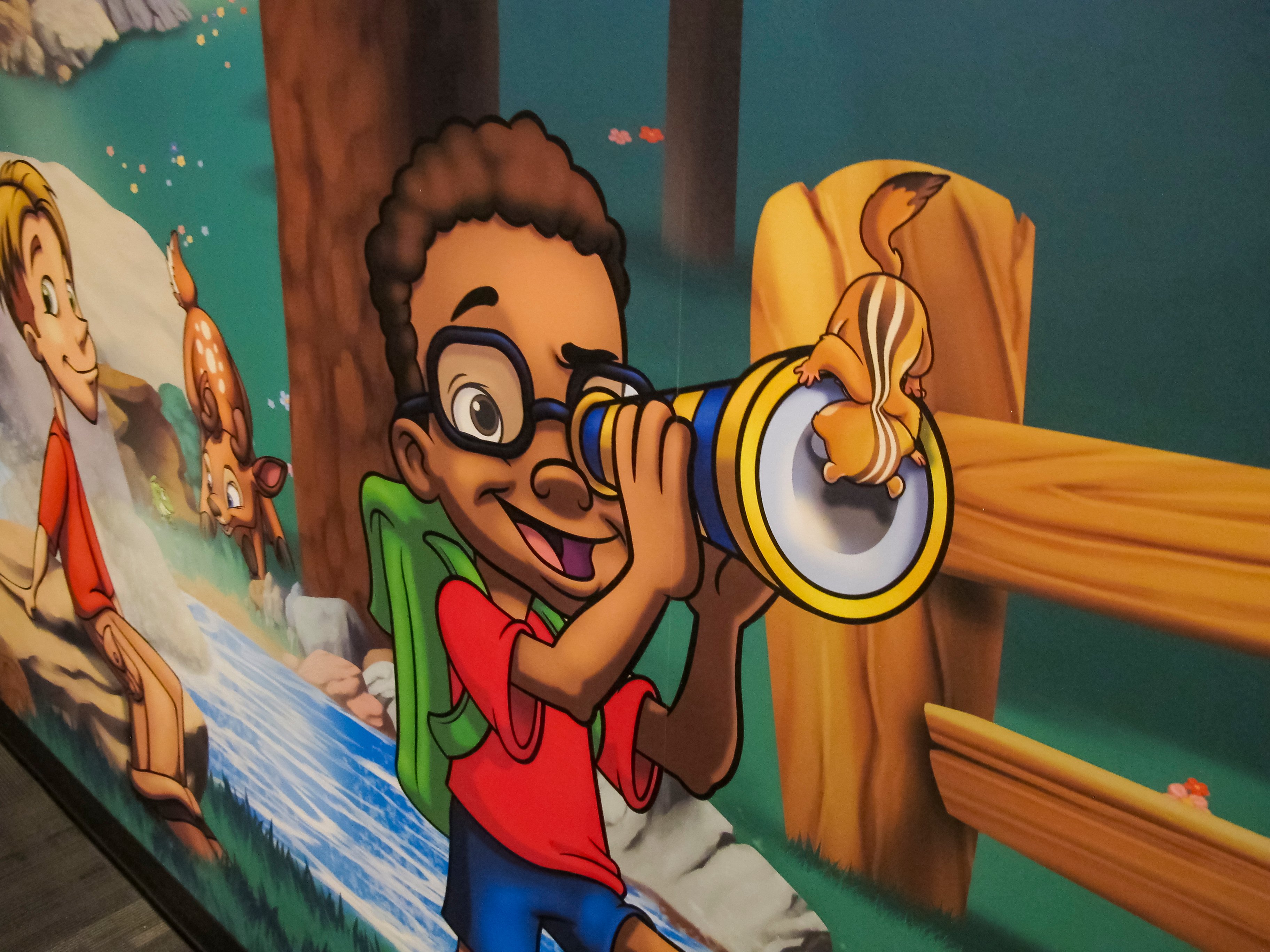 Playful custom mural artwork shows a chipmunk sitting on a child's telescope, showcasing the interactive storytelling details in Faith Community Church's FaithKids ministry.