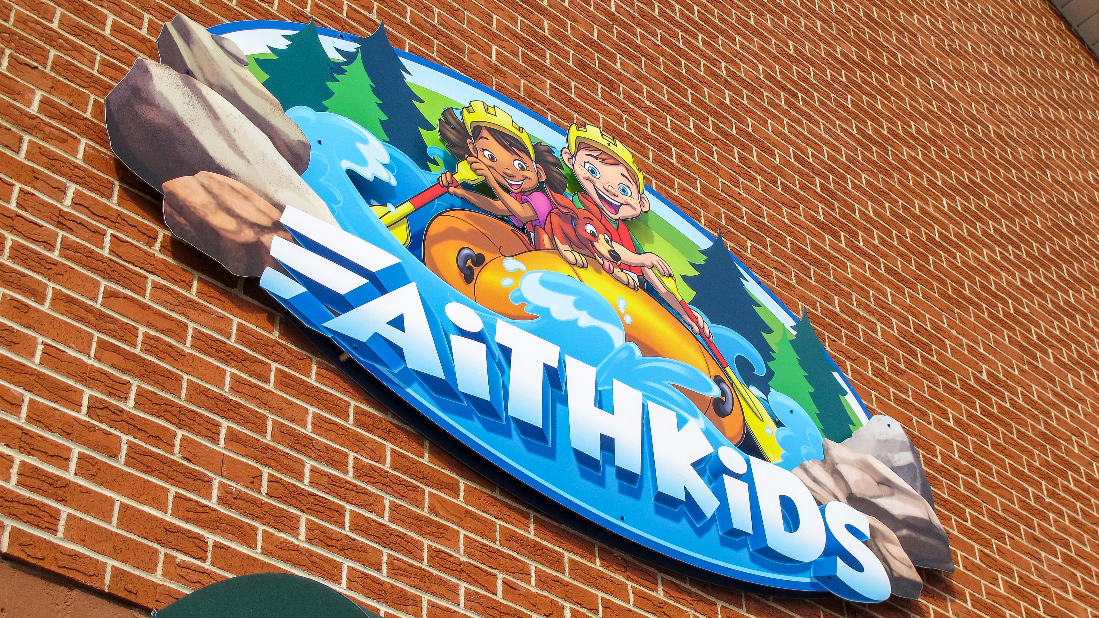 Custom FaithKids outdoor sign with whitewater rafting artwork welcomes families to Faith Community Church's children's ministry.