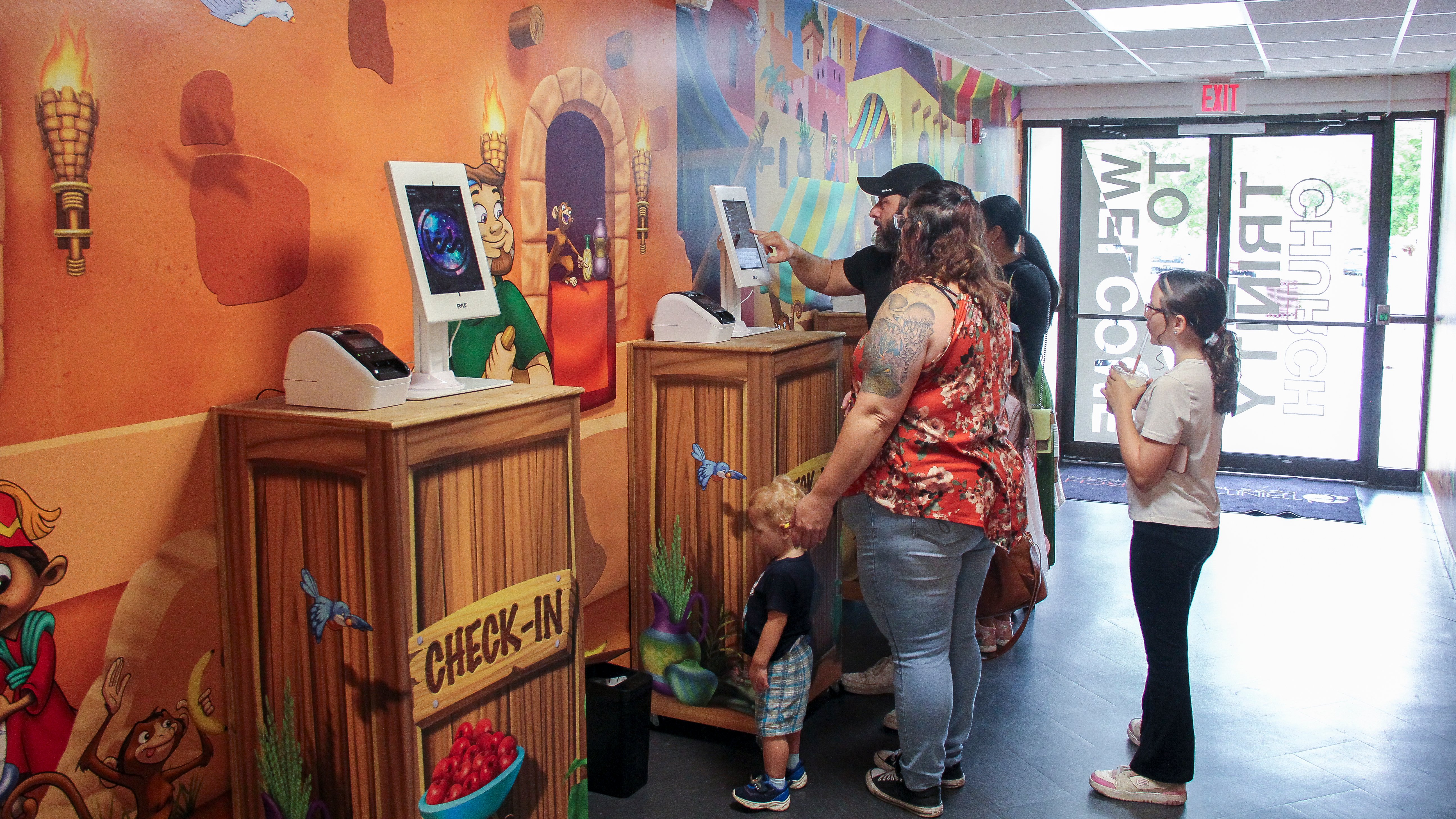 Family checking in at an immersive children's church environment with themed murals and custom kiosks designed to create a welcoming, engaging first impression.