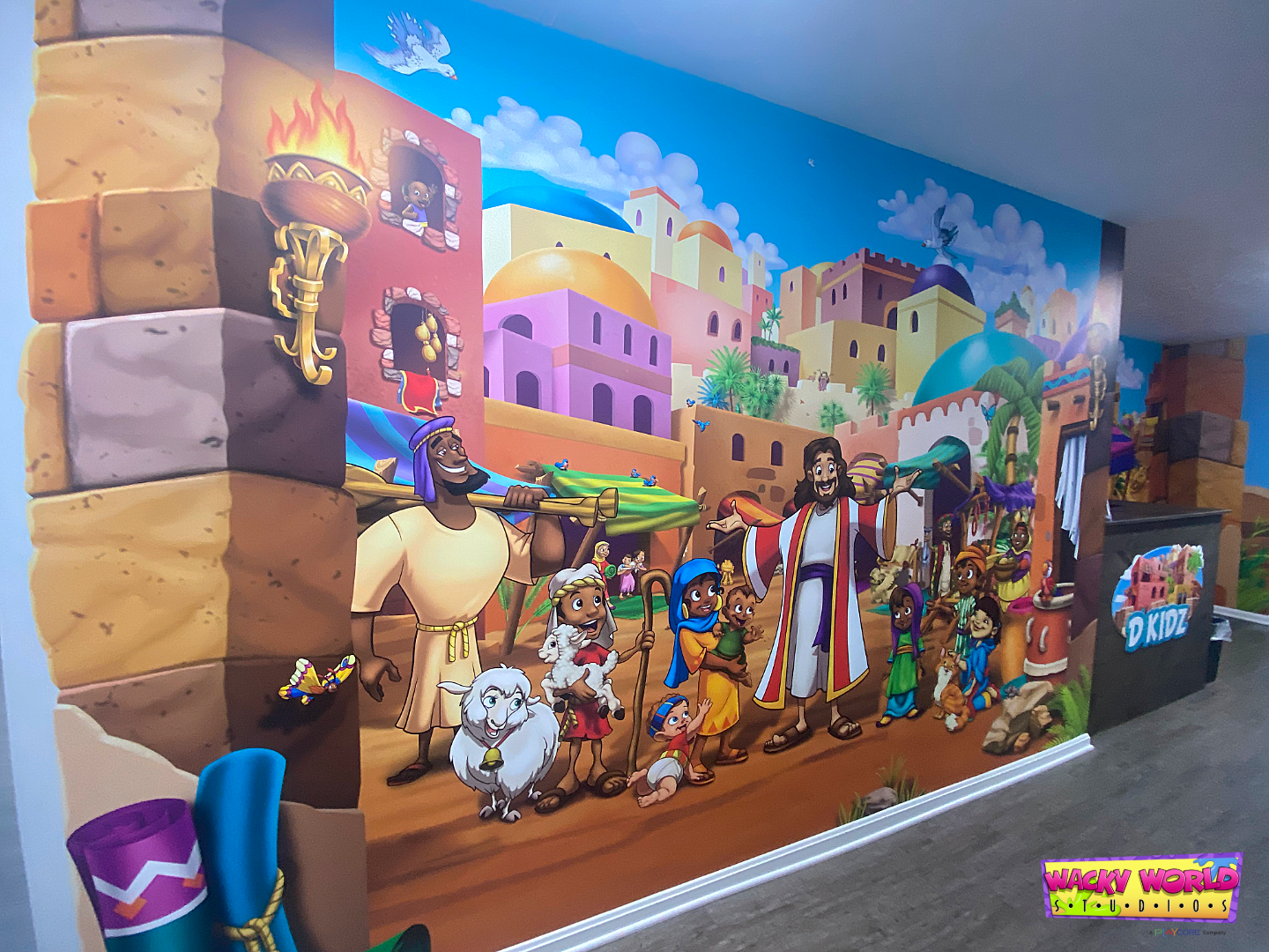 Bible-themed children's ministry mural featuring Jesus and families in a bustling marketplace scene