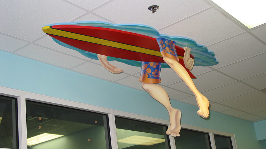 2D Cutout of bottom of Surfboard with hanging surfer legs and arms mounted to the ceiling