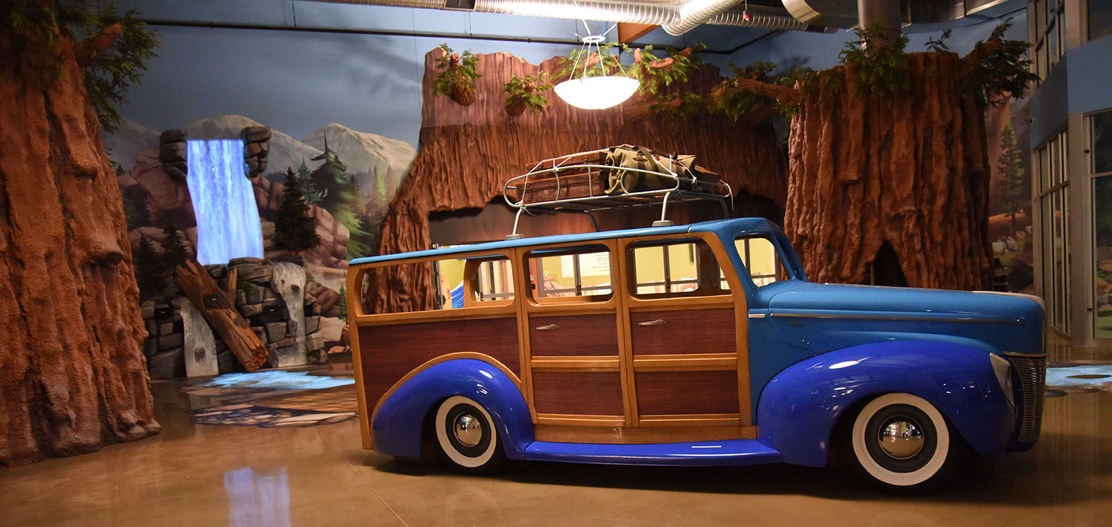 Giant sculpted 3D trees, animated waterfall plus a life-size blue Woody Wagon in a Camping Themed Space at Abundant Life Church
