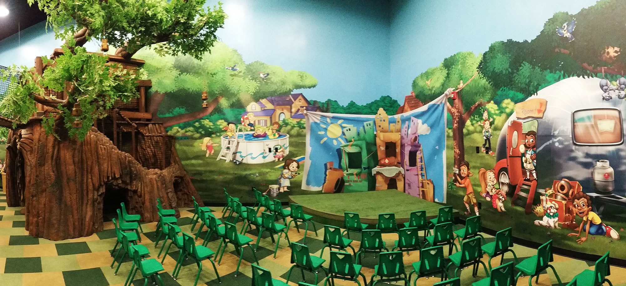 Neighborhood Backyard Treehouse Themed Space with backyard wall mural backdrop, 3D sculpted tree and small quarter circle stage at Choose Life Church