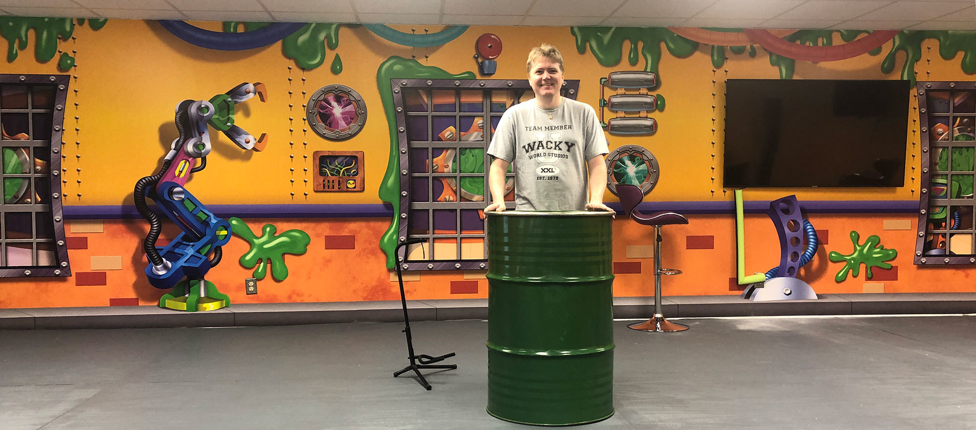 Slime Factory Themed wall mural behind Stage plus Steven Walker behind a green oil drum at London Bridge Baptist Church