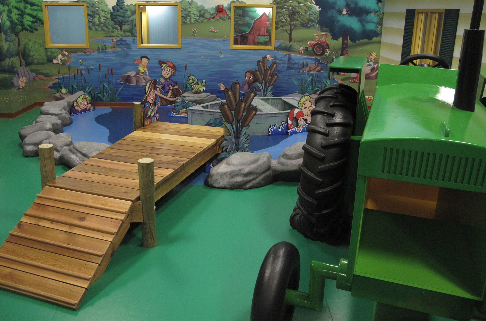 Green Tractor play feature, wooden bridge, faux lake with boat and sculpted rocks and characters in a Farm Themed Environment at Hardin Baptist Church