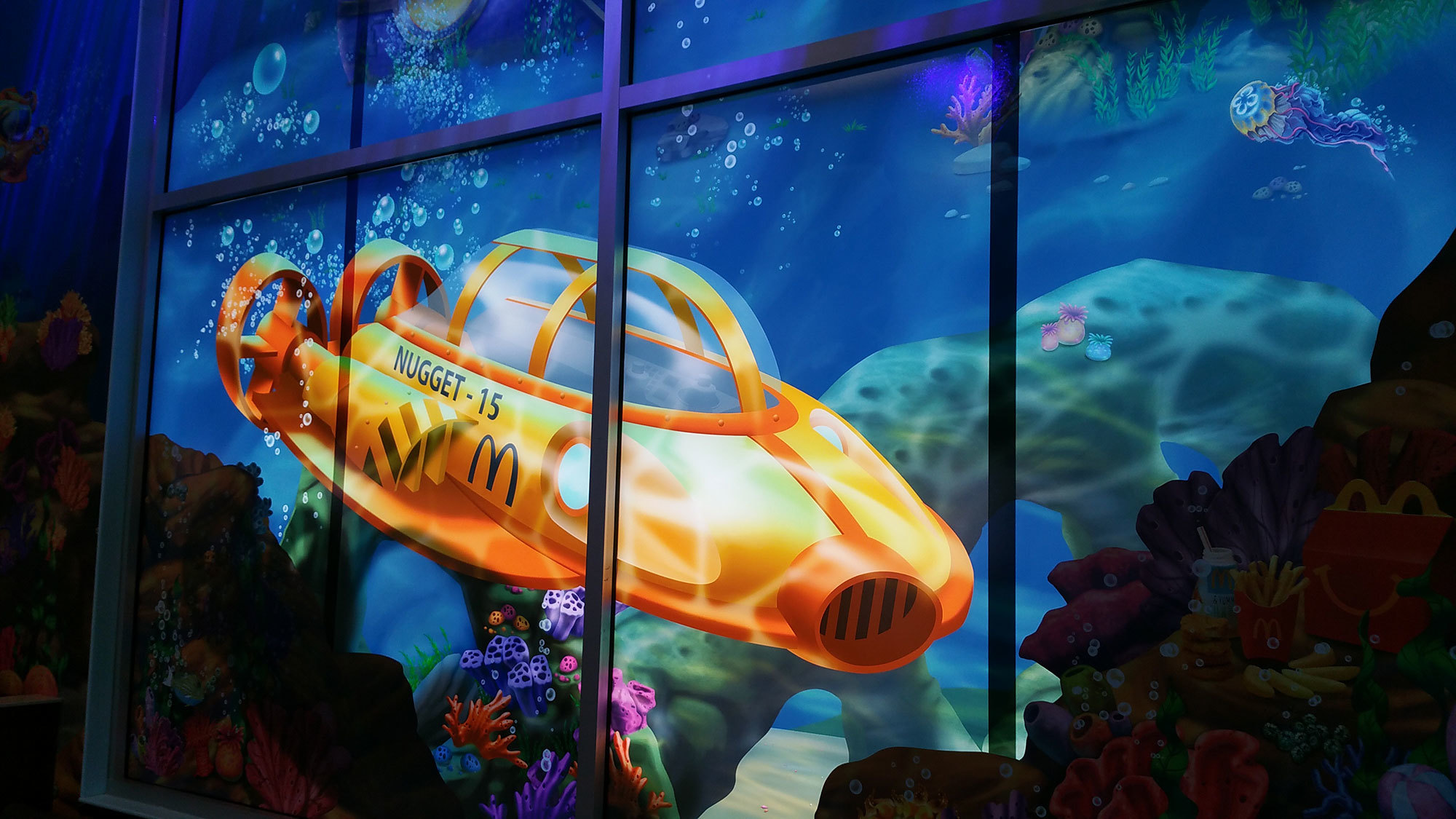 Window graphic of yellow submarine near a coral reef in an Undersea Themed Space at McDonald's
