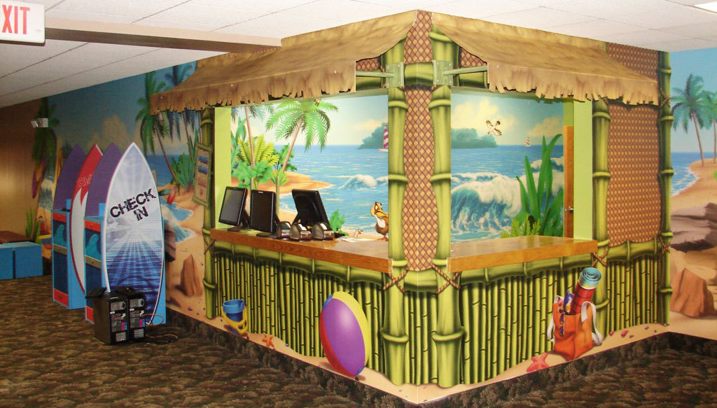 2D surfboard game stations and Beach murals plus Tiki Hut Check In Desk in a Beach Themed space