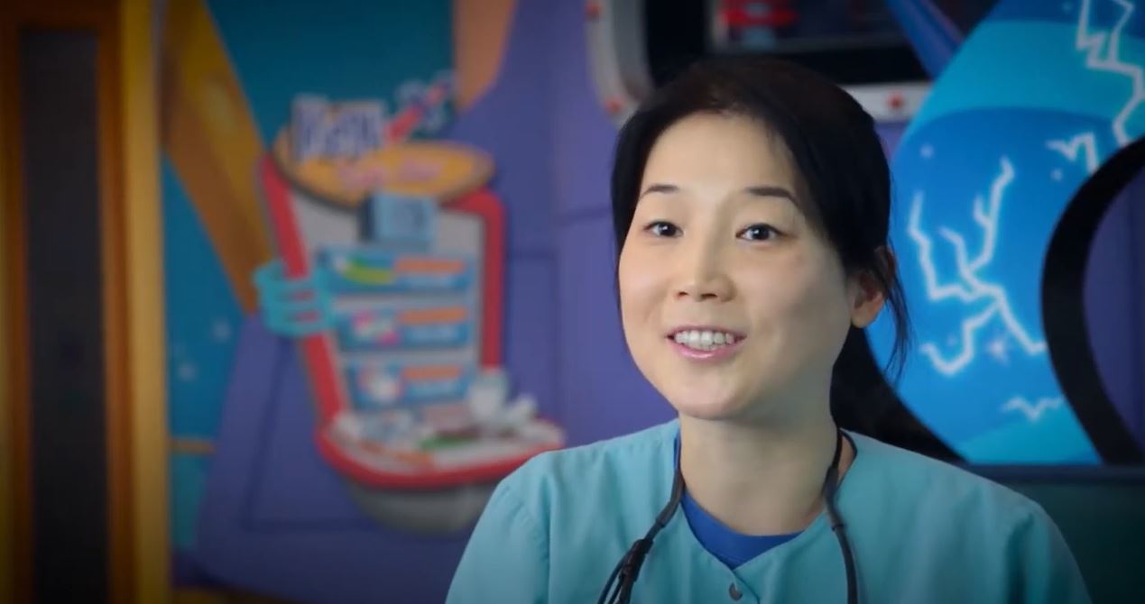 Dr Chen in front of a Space themed mural for a Bright Smiles Pediatric Dentist Testimony Video