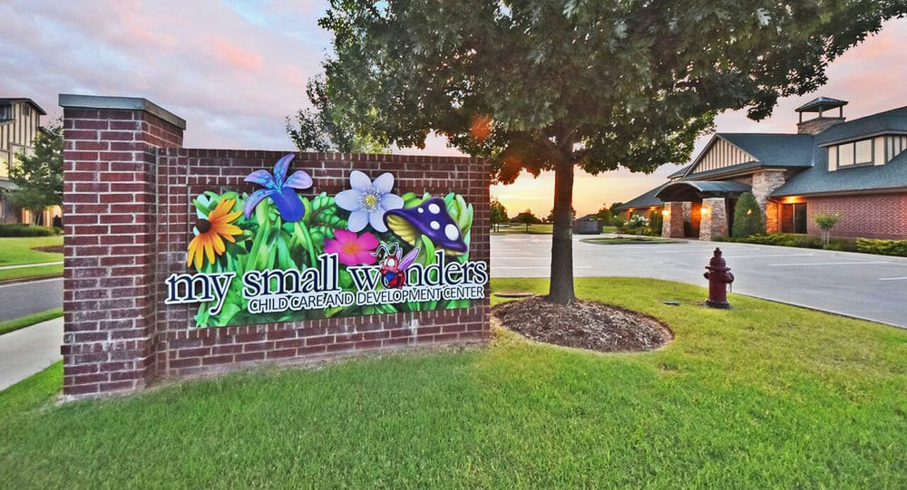 Outdoor Sign with flowers and cartoon bug and letters reading "My Small Wonders Childcare And Development Center".