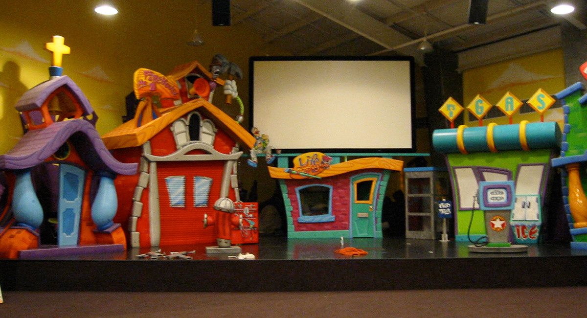 3D sculpted Toon Town buildings as a stage backdrop.