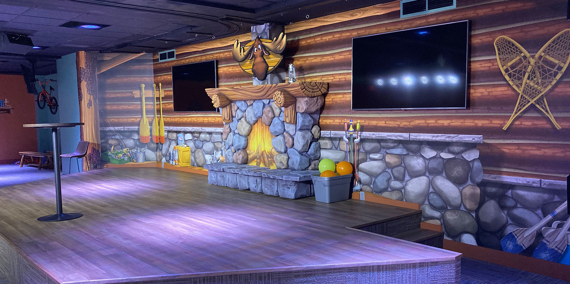 Camping and Lodge Themed Stage with background mural of lodge interior wall and 3D relief sculpted fireplace and moose head,