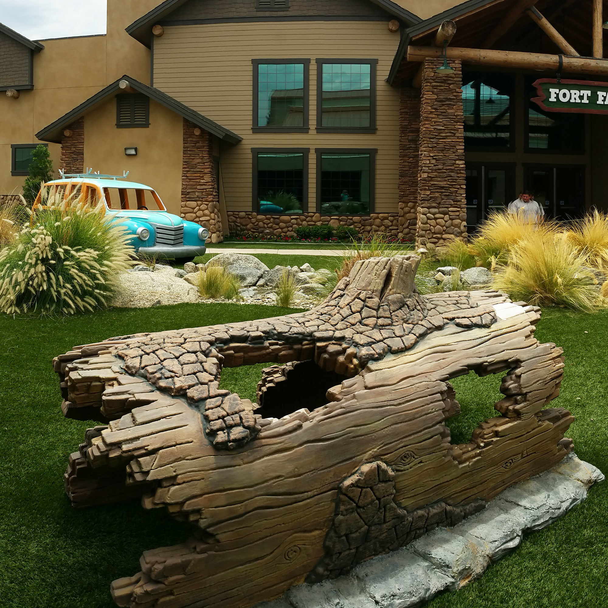 3D sculpted log crawl-thru play feature and 3D sculpted car outside Canyon Hills Church