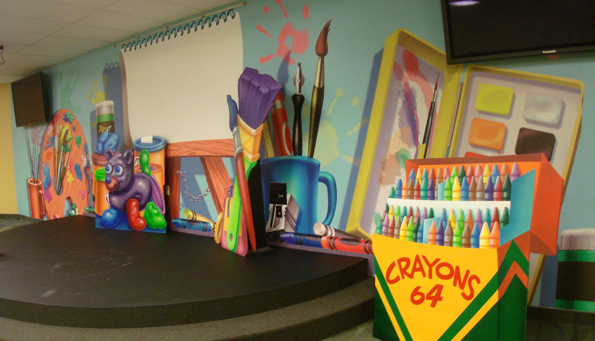 Art Class Themed Environment backdrop for stage at Bent Tree Bible Fellowship with large Easel, Paint Palette, Cup of brushes, 3D Crayons box and more.