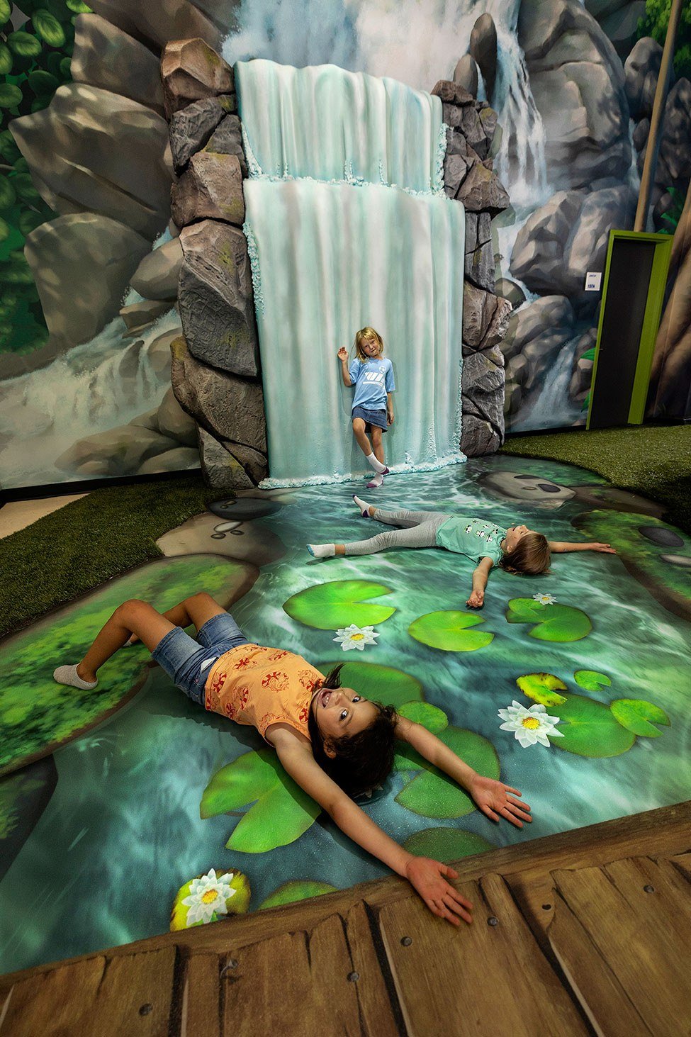 Kids playing in front of waterfall animation feature at West Chicago Parks District ARC Center