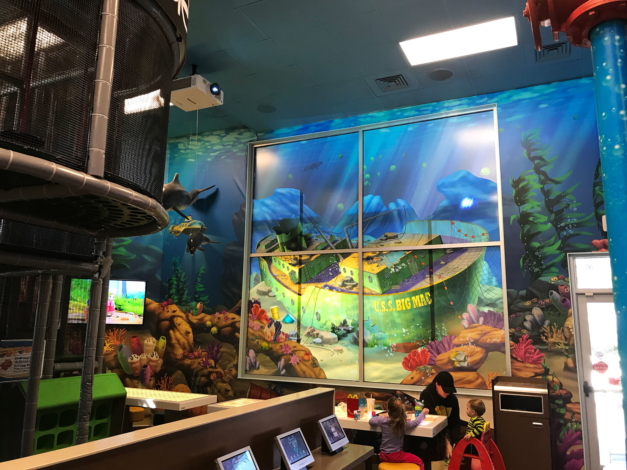Sunken Ship window graphic plus murals of a coral reef and sharks in an Undersea Themed Space at McDonald's