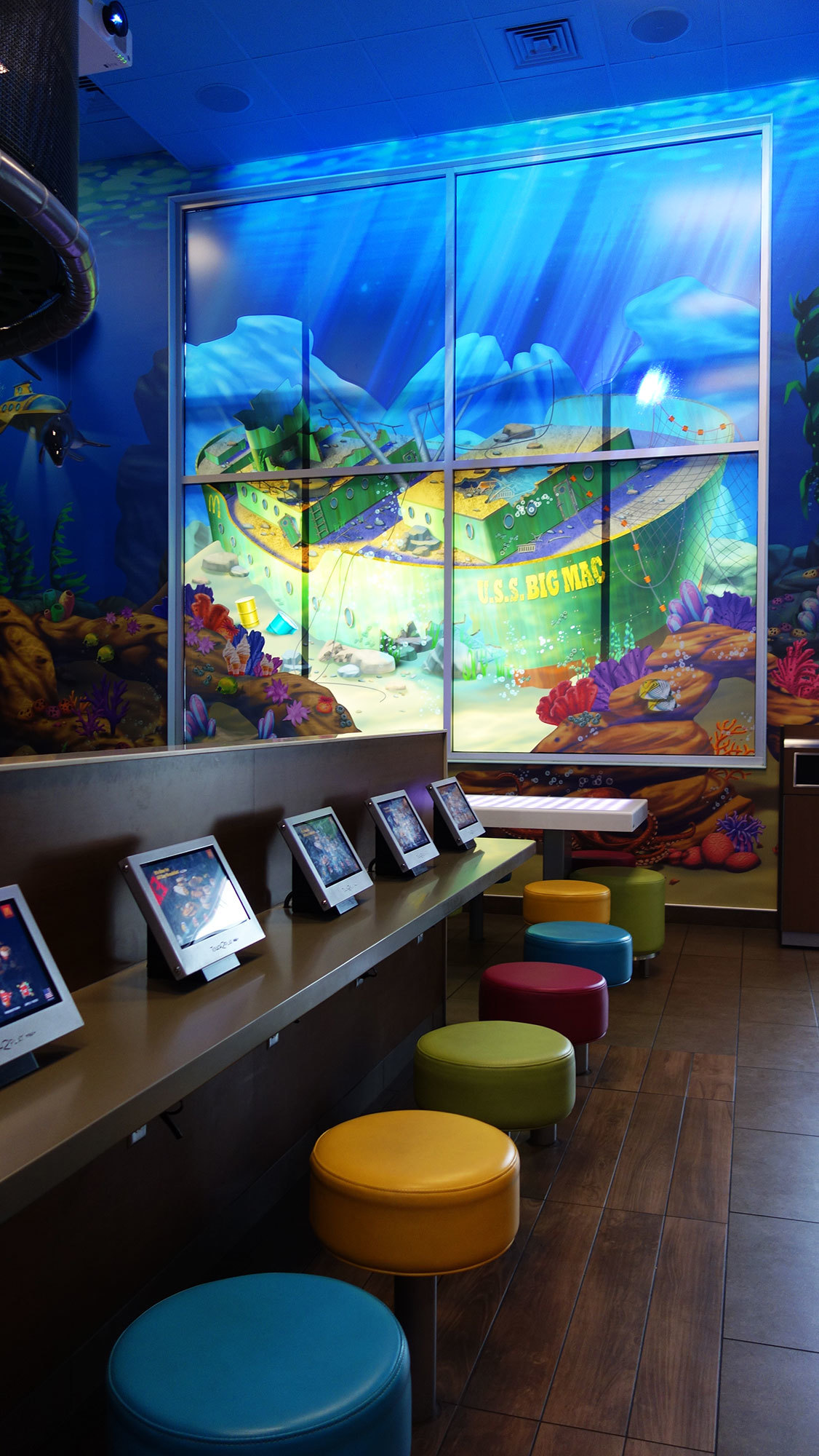 Window graphic of a sunken ship plus a row of seats in an Undersea Themed Space at McDonald's