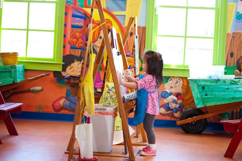 Kid playing at an easel in an Art Class themed environment