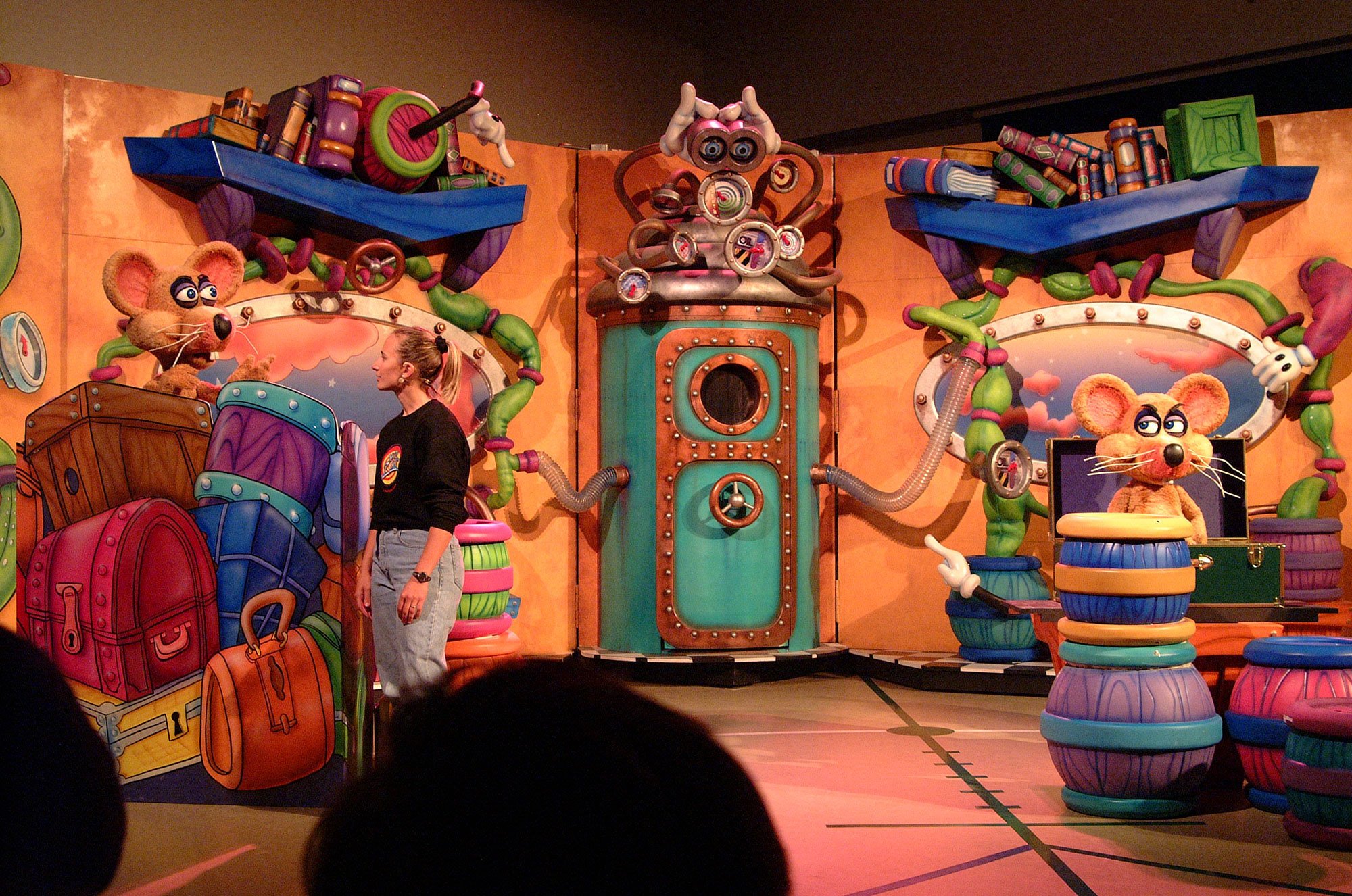 Woman on a Wacky Stage with Animatronic Characters, 3D props, bookshelves, books, pipes and other characters