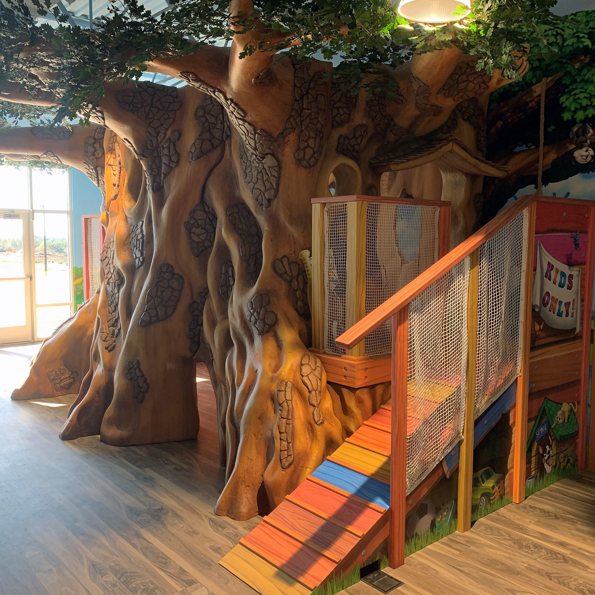 3D sculpted Interactive Treehouse Play Area with colorful ramp, netting and cozy spots at a Church